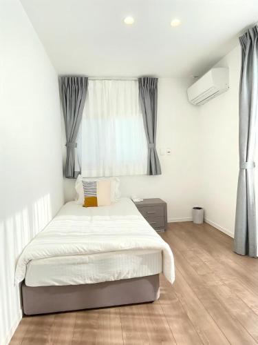a white bedroom with a bed and a window at Akikawa Koshi 8 プレミアム鉄骨 一棟貸切ヴィラ in Yuge