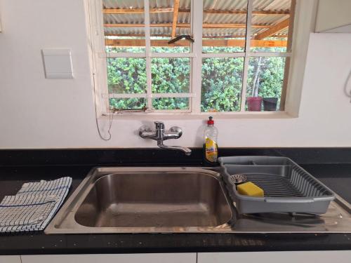 a kitchen sink with a dish rack in it at Siesta Cottage in Howick