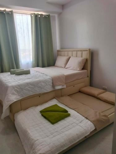 two twin beds in a bedroom with green curtains at Clover88 Studio Room is in the City but with a seaview in Mandaue City