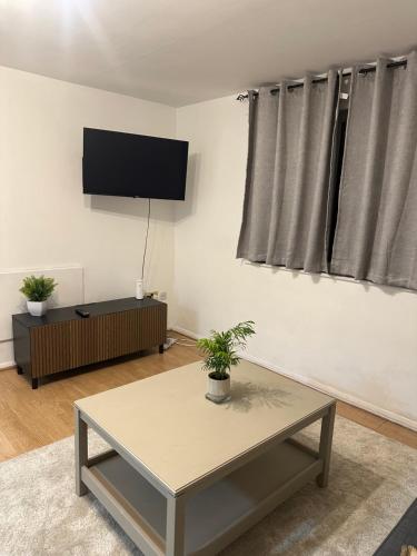 a living room with a table and a flat screen tv at Maya-Ama Cosy 2 Bedroom Flat Near Lakeside Shopping Centre And Grays in West Thurrock