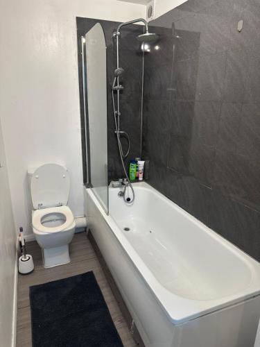 a bathroom with a white tub and a toilet at Maya-Ama Cosy 2 Bedroom Flat Near Lakeside Shopping Centre And Grays in West Thurrock