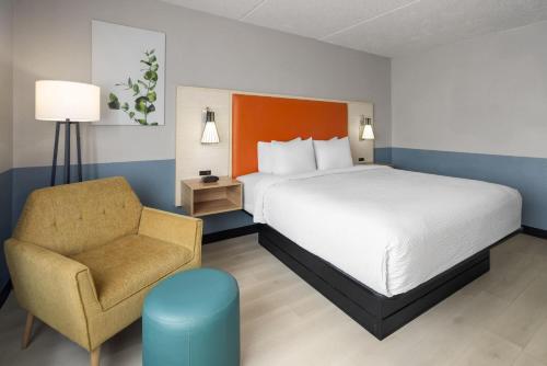 a hotel room with a bed and a chair at Baymont by Wyndham Westampton in Westampton Township