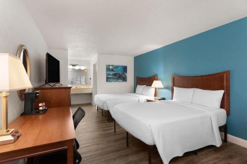 a hotel room with two beds and a desk and a computer at PaddleTail Waterfront Lodge, Trademark Collection by Wyndham in Crystal River