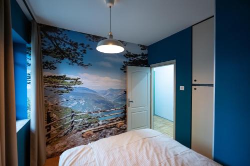 a bedroom with a blue wall with a mountain view at Srafko apartment in Subotica