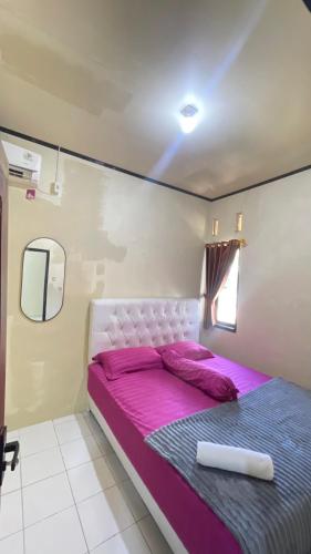 a bed in a room with purple sheets and a pink bedvisor at sarisare homestay 2BR in Bulakbenda