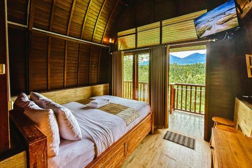 a bedroom with a bed and a large window at Four Mountains Villa Bedugul by AGATA in Bedugul