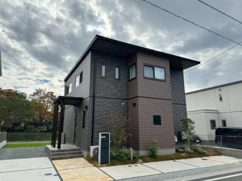 a small brick house with a black roof at Akikawa Koshi 7 プレミアム鉄骨 一棟貸切ヴィラ in Yuge