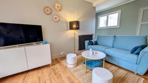 a living room with a blue couch and a tv at Le Saint-Georges in Berck-sur-Mer