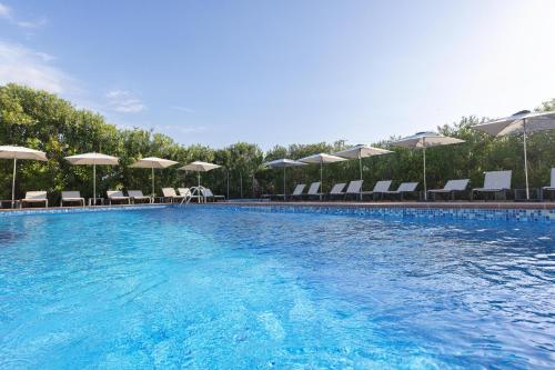 a large swimming pool with chairs and umbrellas at Invisa Hotel Es Pla - Adults Only in San Antonio