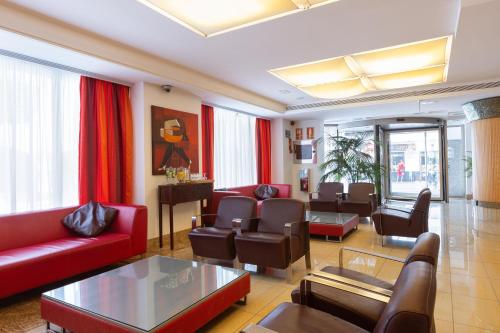 a living room with a red couch and chairs at Invisa Hotel La Cala in Santa Eularia des Riu