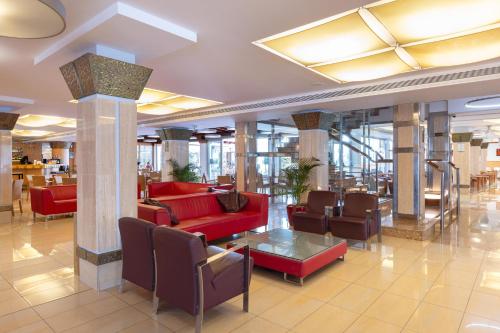 a lobby with red couches and chairs in a building at Invisa Hotel La Cala in Santa Eularia des Riu