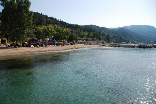 a group of people sitting on the beach next to the water at Hotel Penelope in Boukari
