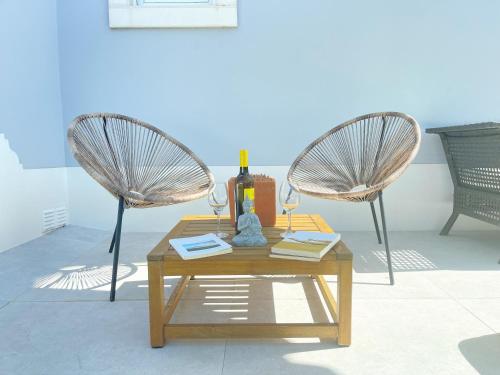 two chairs and a table with a bottle of wine at Oliva Home Ericeira in Ericeira