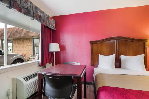 a hotel room with a bed and a desk and a table at Econo Lodge Williamsburg Historic Area in Williamsburg