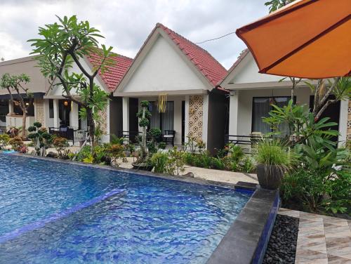 a villa with a swimming pool in front of a house at GHangga Amed in Karangasem