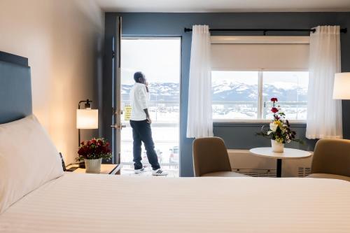 a man looking out the window of a hotel room at SKKY Hotel in Whitehorse