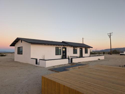 a small white house in the desert with a wooden deck at Golden Moon Hideaway in Twentynine Palms