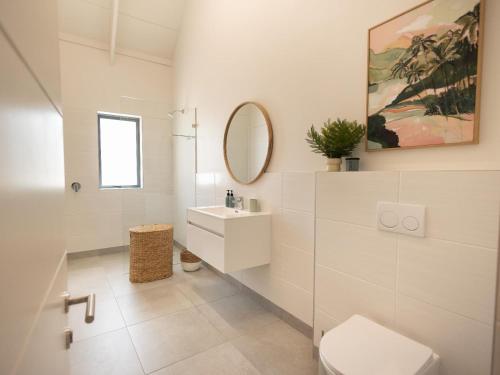 a white bathroom with a toilet and a sink at Cornercade | Unit 1 in Hermanus