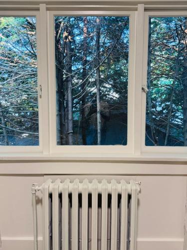 a window in a room with a radiator and trees at Modern Queen Room Ensuite Bathroom Vancouver West in Vancouver