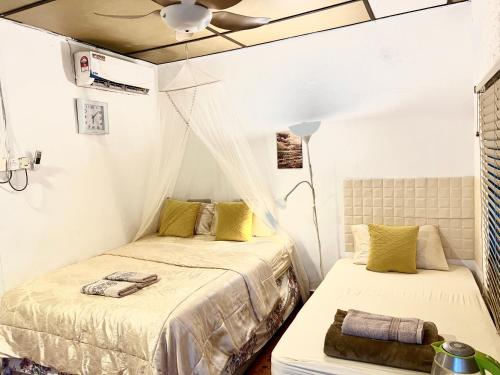 a bedroom with two beds and a ceiling fan at Dar Yasmine in Pantai Cenang