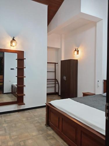a bedroom with a bed and a dresser and a mirror at Villa Nuelumalee UpStairs in Hikkaduwa