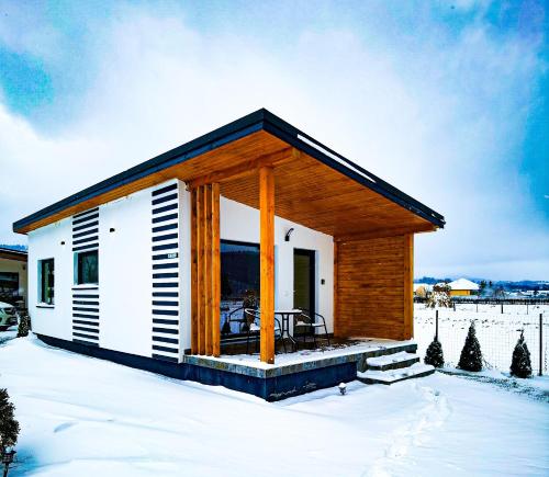 a tiny house with a porch in the snow at F A N BunGALow Vama Buzăului in Vama Buzăului