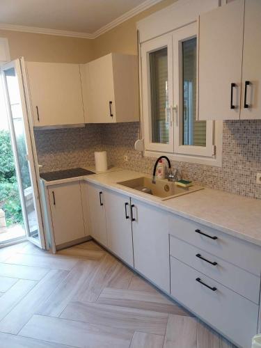 a kitchen with white cabinets and a sink at Villa Kalliope in Nénita