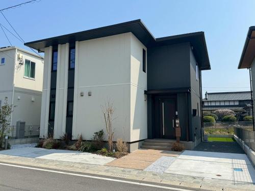 a white house with a black door on a street at Akikawa Koshi 9 プレミアム鉄骨 一棟貸切ヴィラ in Yuge
