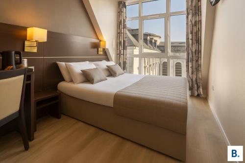 a bedroom with a bed and a large window at Hôtel Croix des Bretons - Lourdes Pyrénées in Lourdes