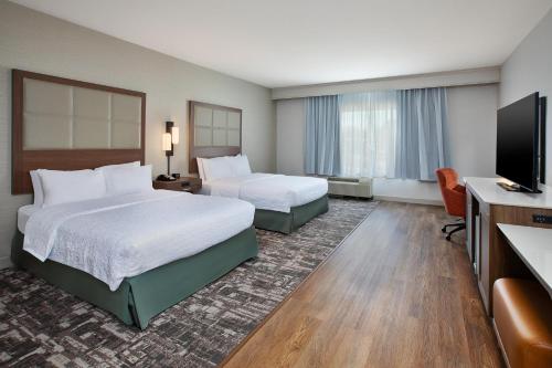 a hotel room with two beds and a flat screen tv at Hampton Inn North Little Rock McCain Mall, AR in North Little Rock