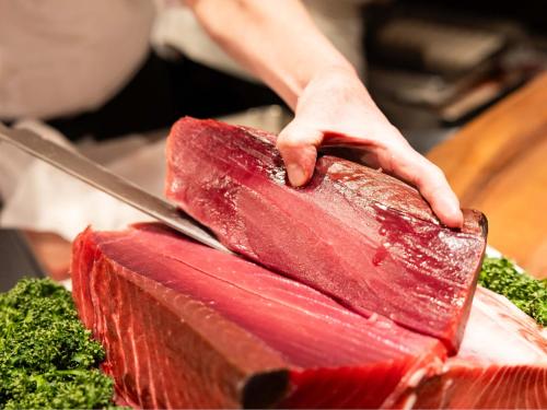 a person cutting a piece of meat with a knife at Hotel Abest Sapporo in Sapporo