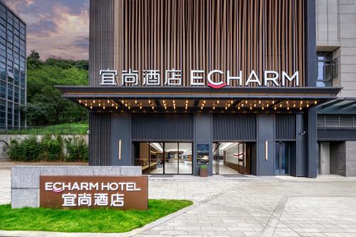 a hotel building with a sign in front of it at Echarm International Hotel Guangzhou Huangpu Flagship Shuixi Subway Station Branch - Free Deliver Service to Guangzhou Baiyun International Airport & Free Deliver Service to Canton Fair Complex During Canton Fair Period in Guangzhou