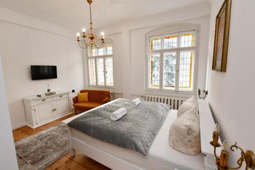 a bedroom with a bed and a chair and windows at Villa Märchenland in Kurort Altenberg