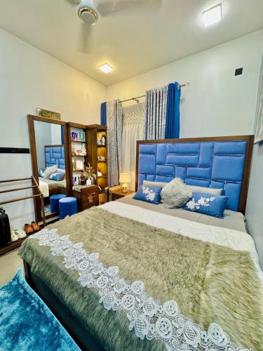 a bedroom with a large bed with a blue headboard at Serandib Town Apartment in Weligama