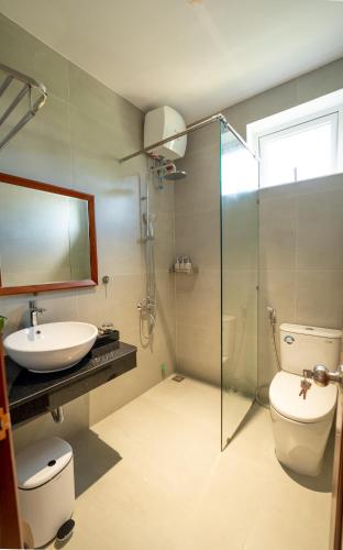 a bathroom with a sink and a toilet and a glass shower at Kim Luông Homestay in Thôn An Hòa