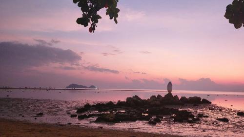 a beach with a statue in the water at sunset at Feel home Private Studio in Ko Phangan