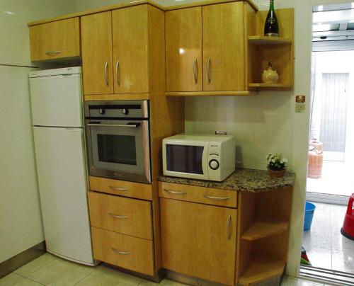 a kitchen with wooden cabinets and a microwave and a refrigerator at La Casa del Centre in Tárrega