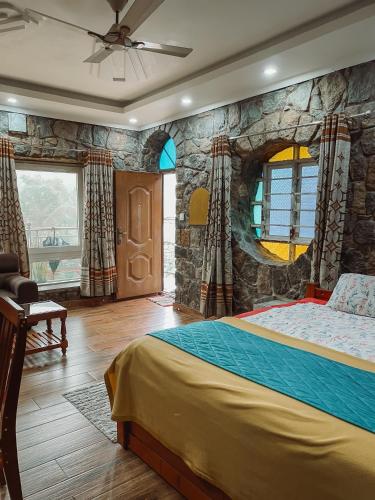 a bedroom with a large bed with a stone wall at Vaga Copper Castle in Vagamon