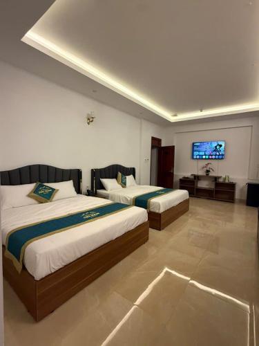 a hotel room with two beds and a flat screen tv at Hải Nam Hotel Tây Ninh in Tây Ninh