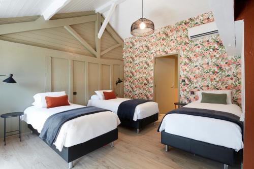 a room with two beds and a floral wall at Domaine de Barthas in Castelnau-Magnoac