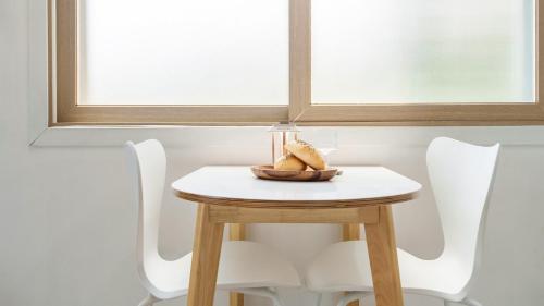 a small table with two white chairs and a window at Yeosu falling in blue ocean view pension in Yeosu