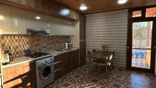 una cucina con una lavatrice e un tavolo di Mountain Hearth a Vǝndam