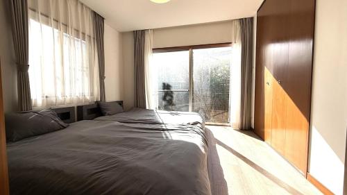 a bedroom with a bed and a large window at kamakura retreatB in Kamakura