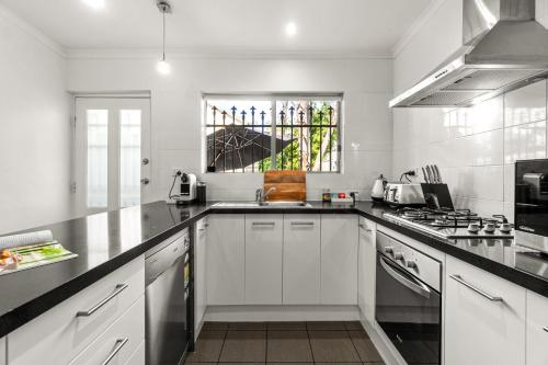 a white kitchen with a sink and a stove at The Arches-Beautiful 3-Bedroom Family Stay Near Adelaide Oval, City Events and Amazing Dining in North Adelaide