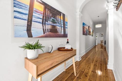 a hallway with a table with a bottle of wine at The Arches-Beautiful 3-Bedroom Family Stay Near Adelaide Oval, City Events and Amazing Dining in North Adelaide