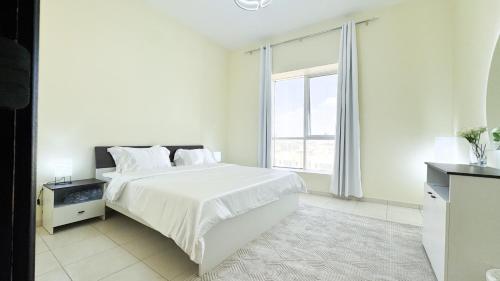 a white bedroom with a large bed and a window at Spacious 2BR Apartment,3 Bathrooms, Near Mall in Abu Dhabi