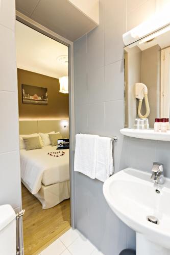 une salle de bain avec un lavabo, un lit et un miroir dans l'établissement Modern Hotel, à Paris