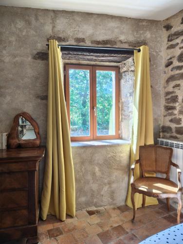 a window with yellow curtains and a chair in a room at Mine d'Ore Petit Gîte de la Chouette d'Or in Thoste