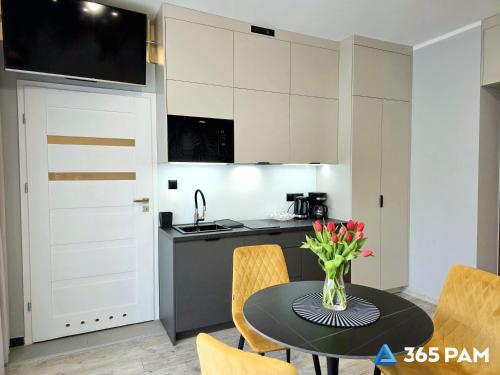 a kitchen with a table with a vase of flowers on it at 365PAM - Studio Dominikańska Szóstka - Z PARKINGIEM W CENIE, KRYTY BASEN W OBIEKCIE in Sianozety