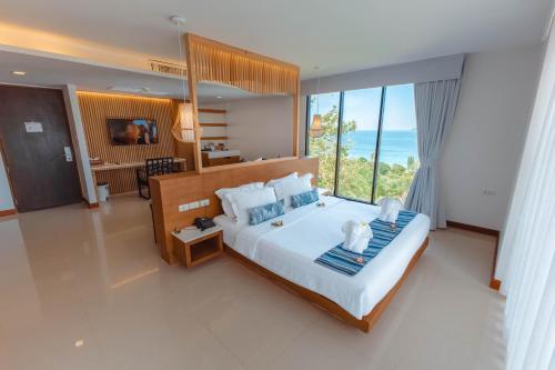 a bedroom with a large bed with a view of the ocean at Peach Blossom Resort & Pool Villa - SHA Plus in Kata Beach